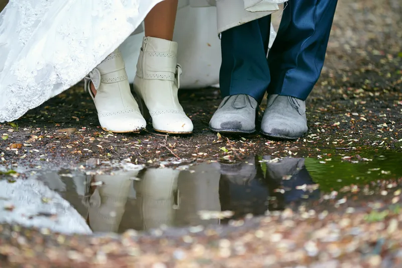 De schoenen van Elise en Maarten weerspiegelen in een plas