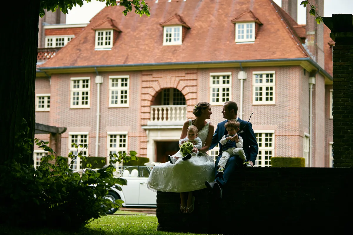 Elise en Maarten met twee kinderen in het gras, met het landhuis erachter