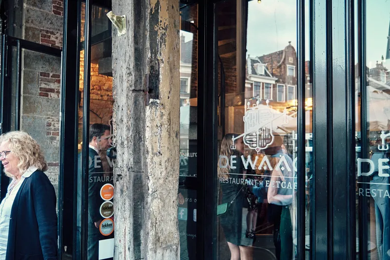 Een gast bij de glazen deur van De Waag