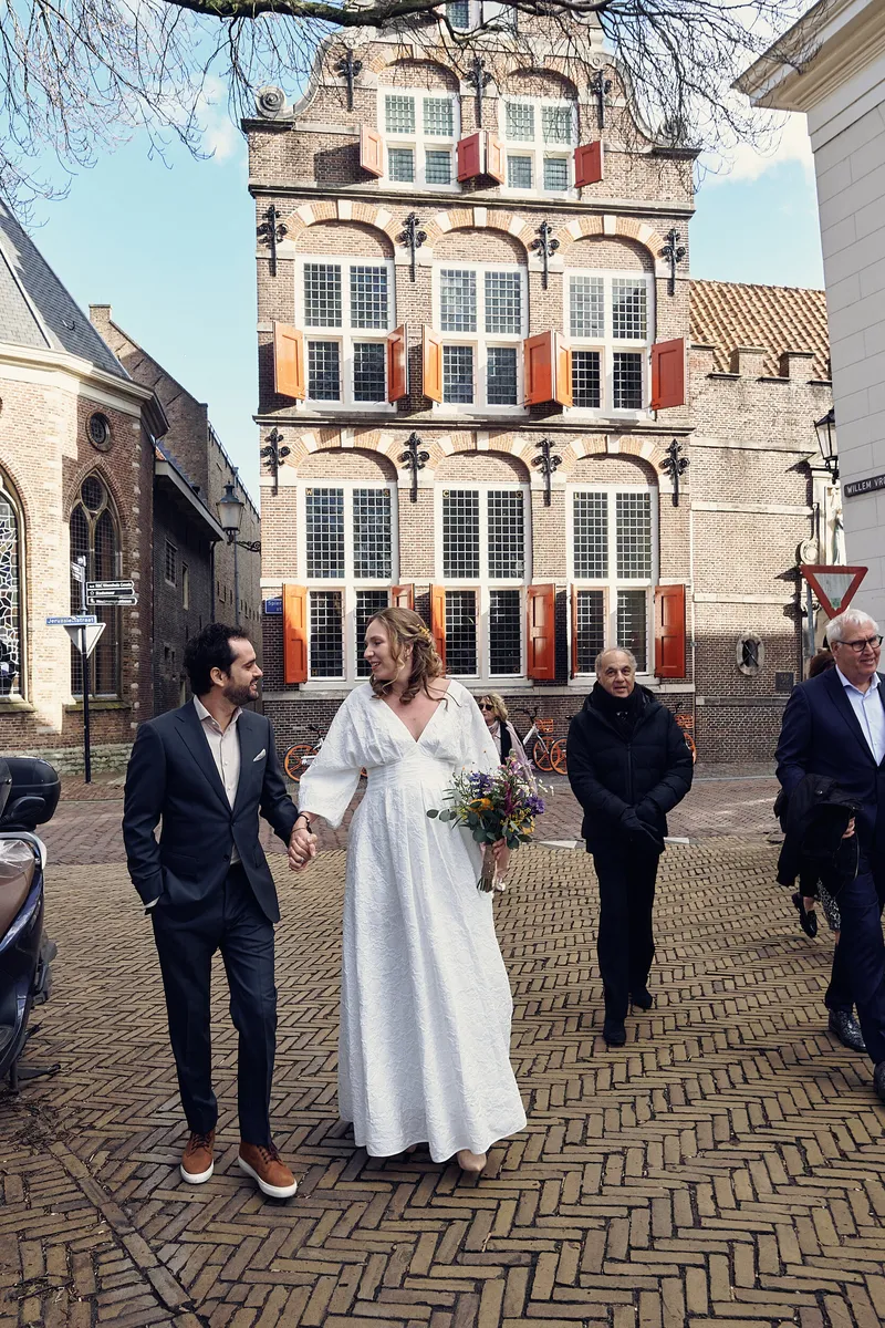 Anouk en Raphaël lopen hand in hand, met het weeshuis en de familie achter hen