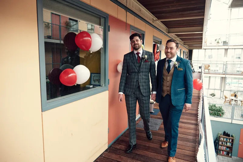Joey en Twan lopen over de galerij, langs de ramen met rode ballonnen