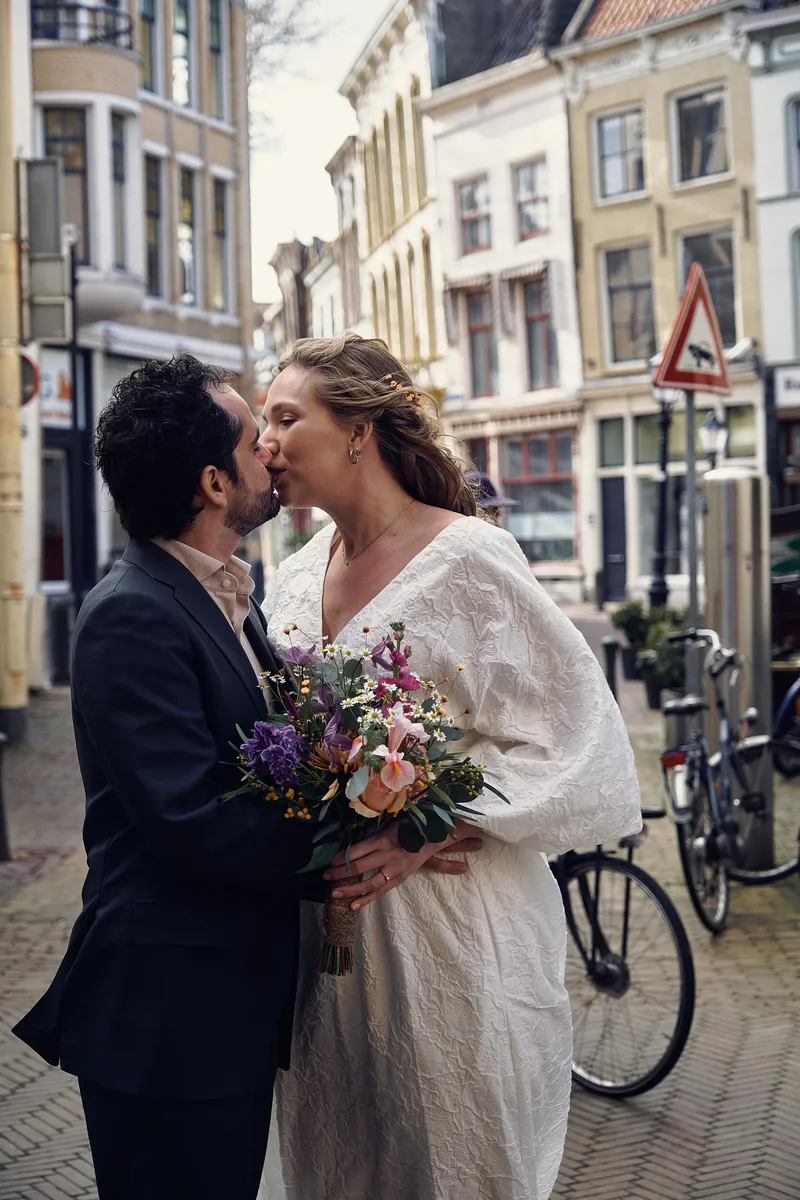 Raphaël kust Anouk in een winkelstraat, naast een fiets