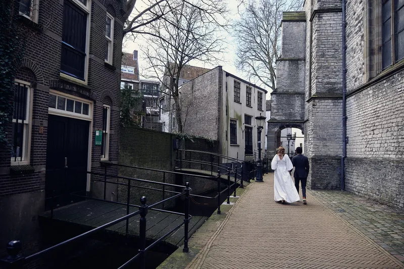 Een smal straatje langs het water, met het bruidspaar in de verte