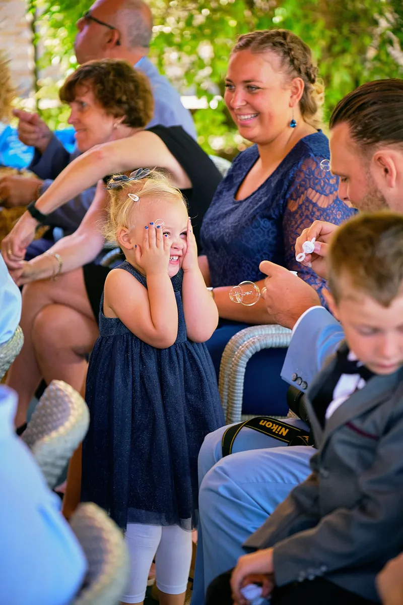Een meisje houdt haar handen voor haar ogen tussen de gasten