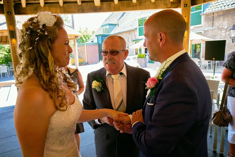 Chantal en Ramon schudden een man in pak de hand onder het afdak
