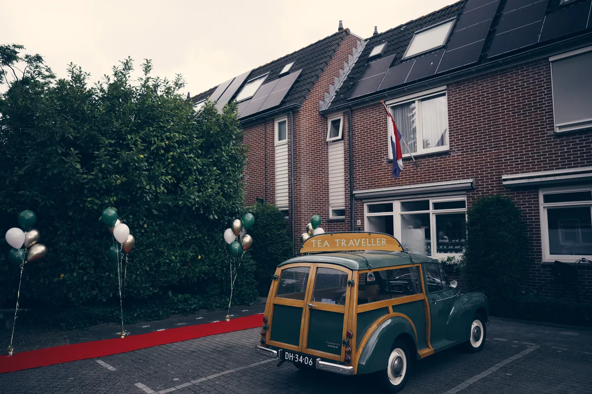 Een oldtimer voor de deur, met een rode loper en ballonnen in Wassenaar
