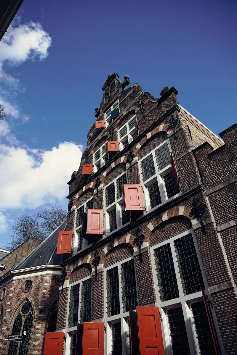 De gevel van Hotel Weeshuis met rode luiken en roze hartjes tegen de blauwe lucht