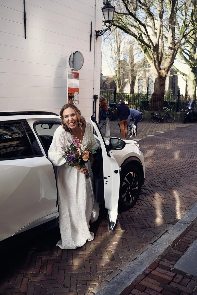 Anouk stapt uit de auto voor het hotel, met haar boeket