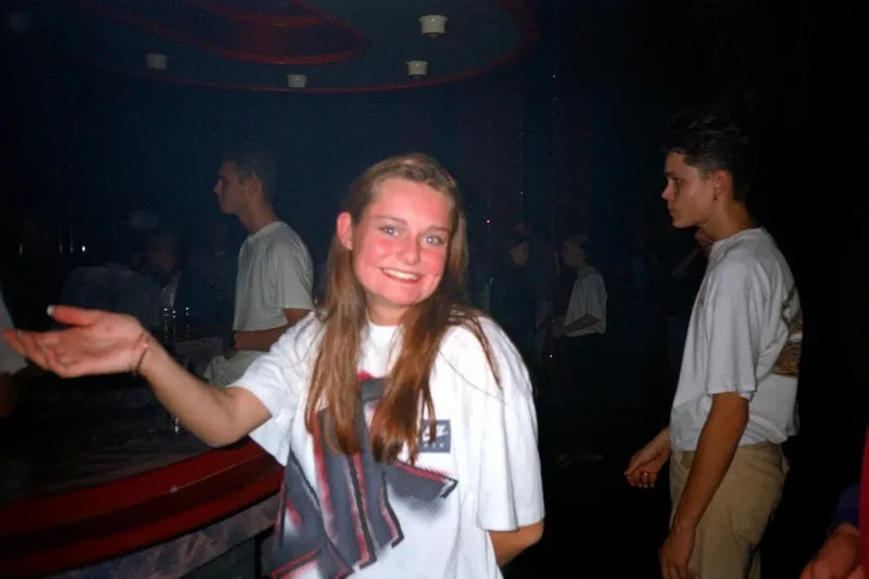 Wegwerpcamerafoto van een meisje op een feest, met harde flits en een donkere achtergrond