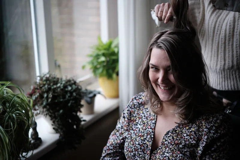 Wendy lacht terwijl haar haar wordt gedaan bij het raam