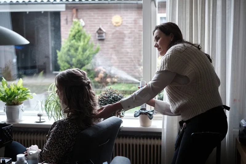 Het haar van Wendy wordt opgestoken in de woonkamer