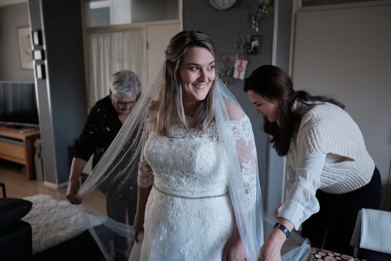 Wendy lacht in haar trouwjurk terwijl de sluier wordt vastgezet