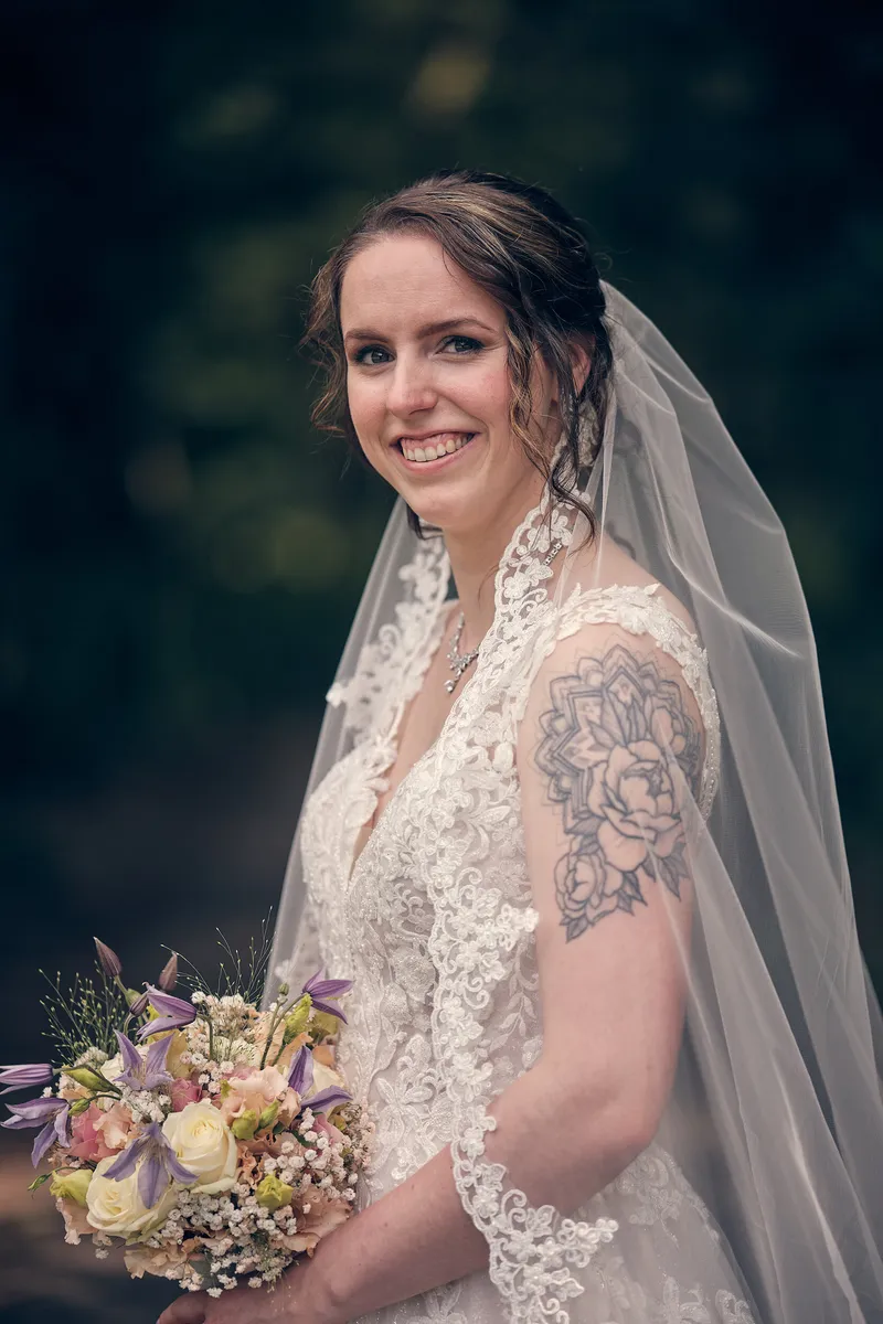 Wendy met haar boeket en sluier, lachend in het groen