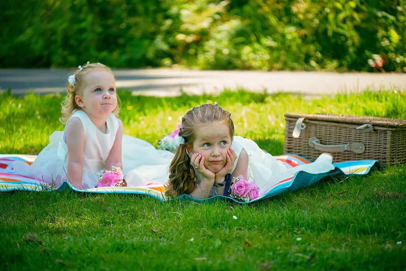 Twee meisjes liggen op een picknickkleed in het gras
