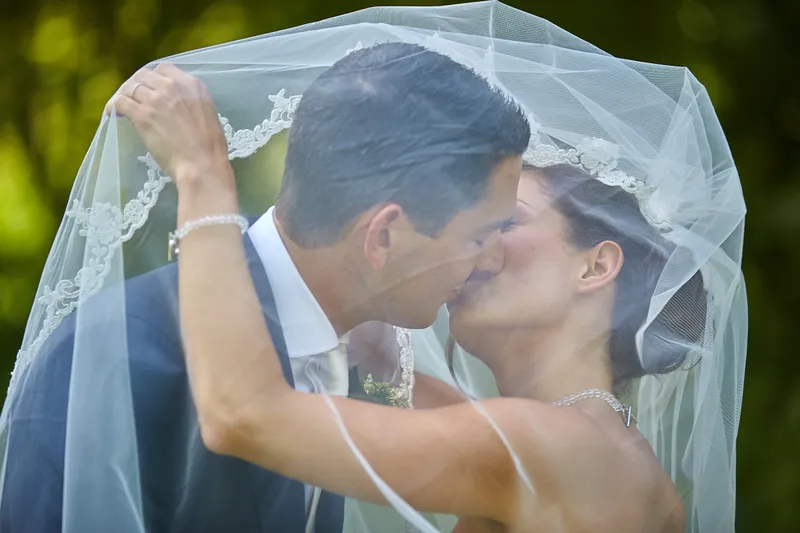 Sanne en Patrick kussen onder de sluier