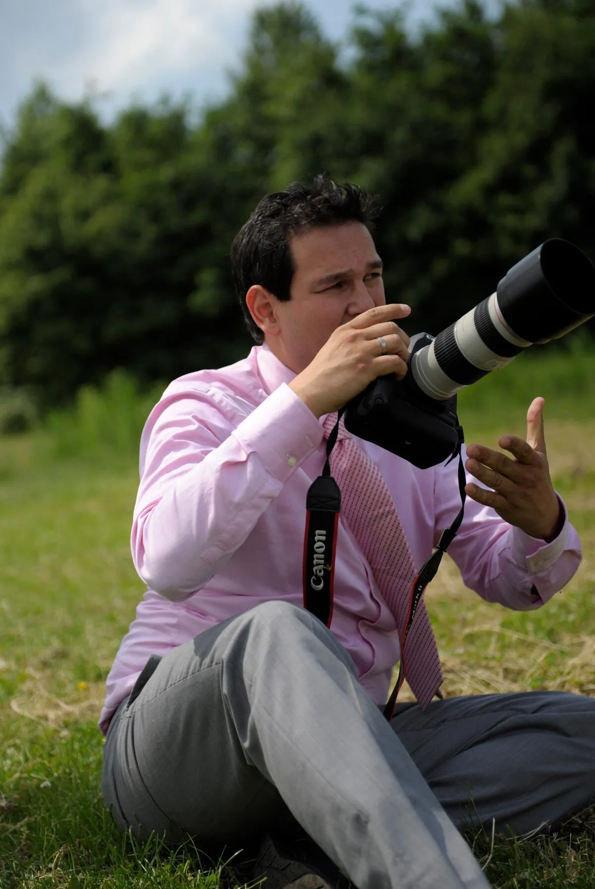 Stefan zit in het gras met een telelens