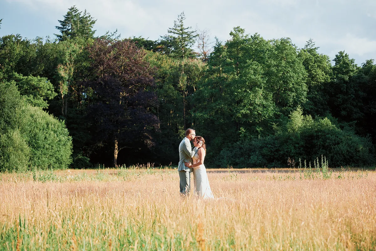 Romana en Sander in een veld met hoog gras, met de bomen van het landgoed erachter