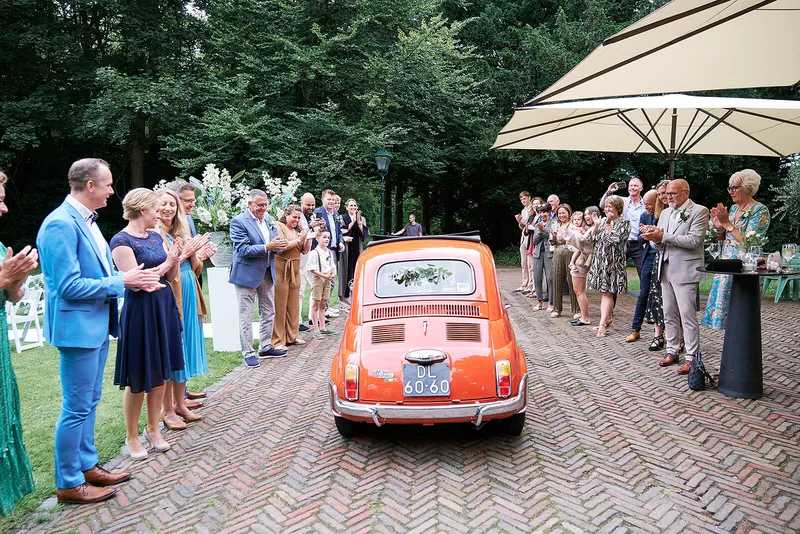 De rode Fiat 500 rijdt tussen twee rijen gasten door naar het landhuis
