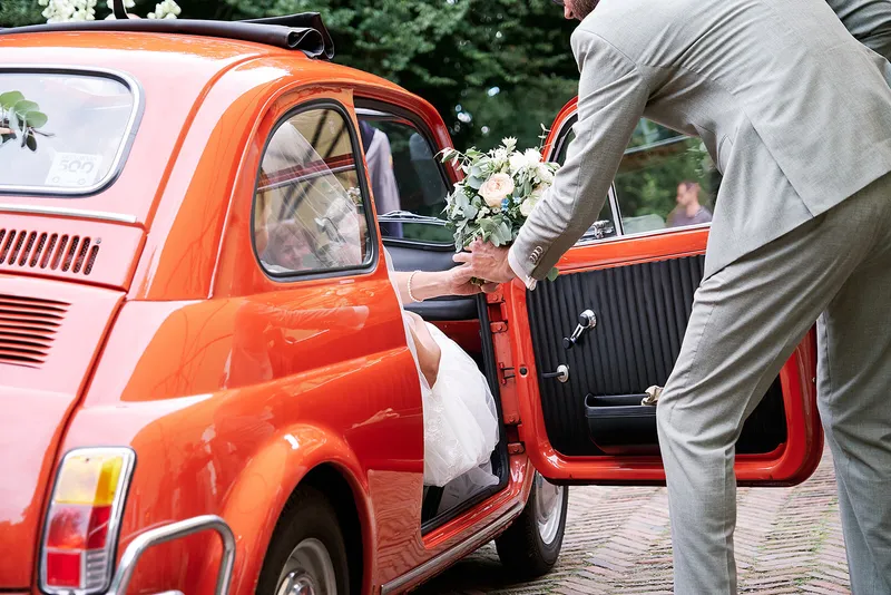 Sander houdt het portier van de Fiat 500 open voor Romana
