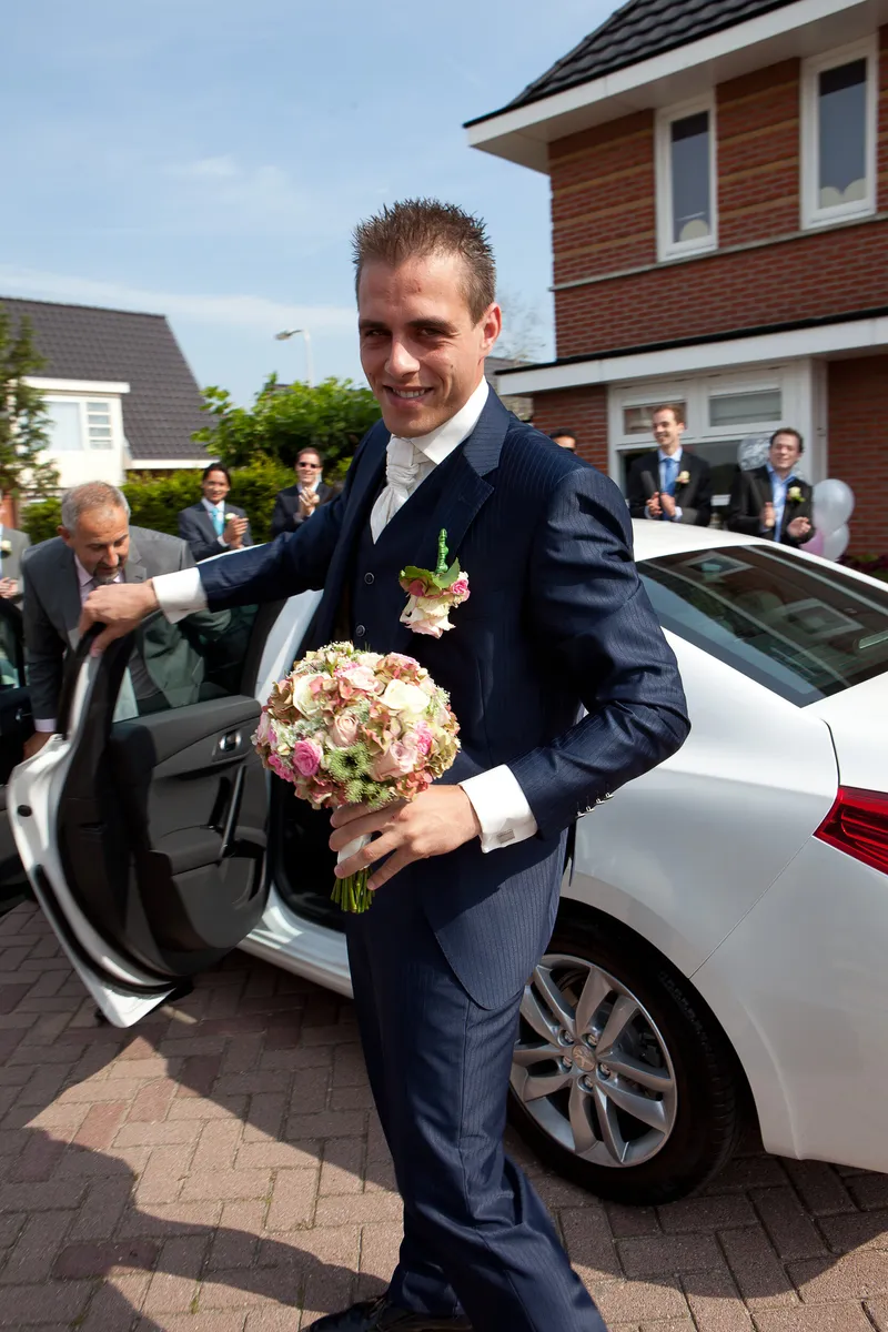 Sebastiaan stapt uit de witte Peugeot met het boeket