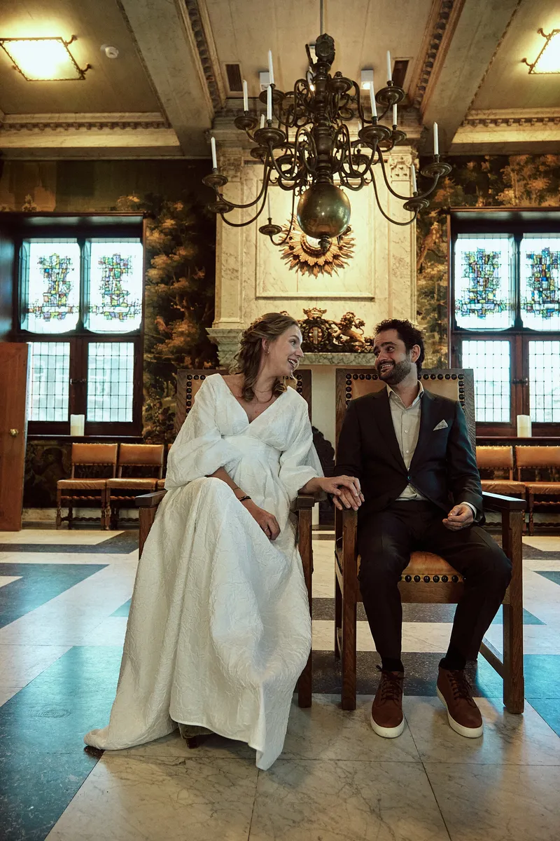 Anouk en Raphaël zitten voor de schouw, onder de kroonluchter